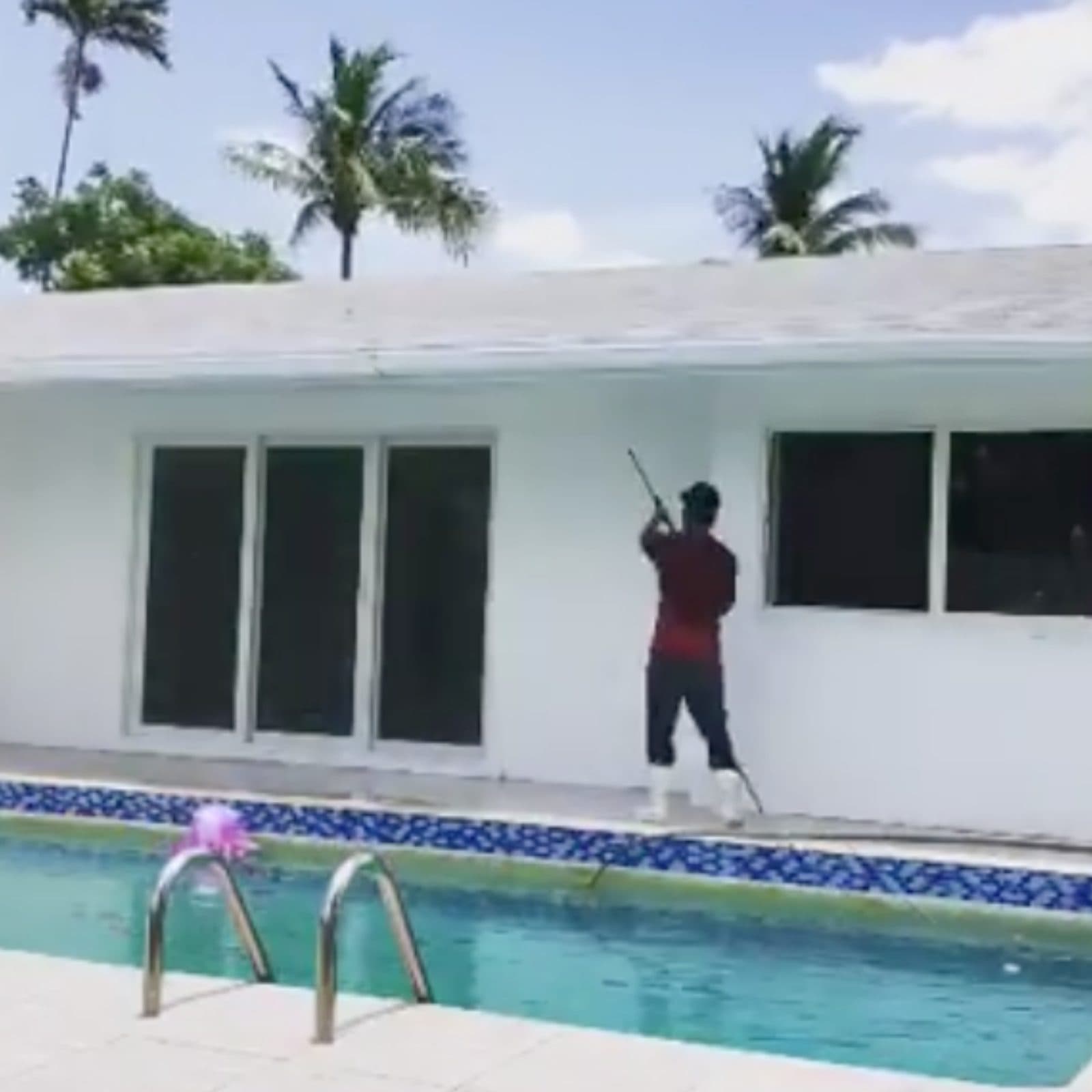 Crew washing an exterior wall with an extension pole beside a pool — Finesse Cleaning, South Florida